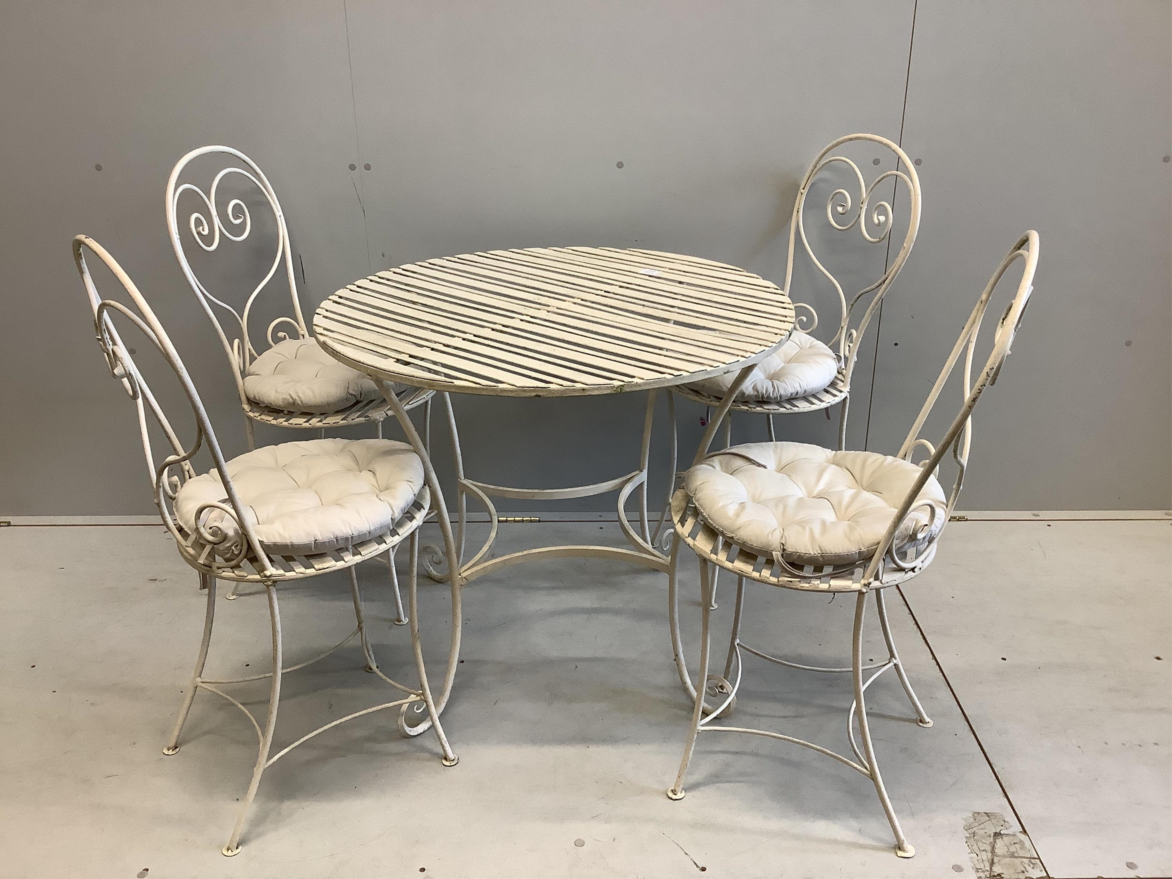 A Camelia Botnar circular wrought iron garden table, diameter 88cm, height 74cm together with four chairs with seat pads. Condition - fair